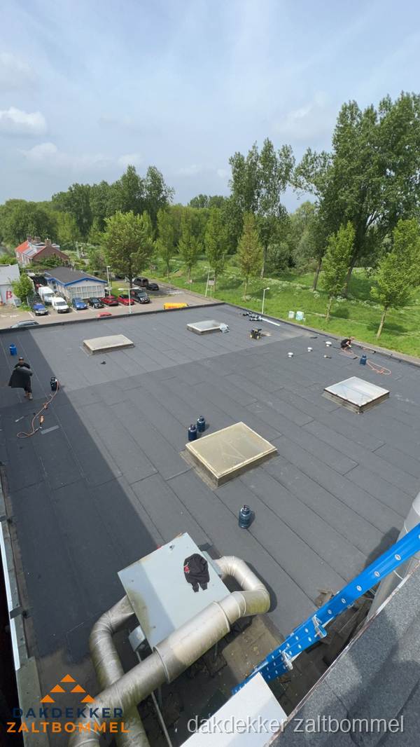 Dakdekker aan het werk op groot plat dak met bitumen in Zaltbommel