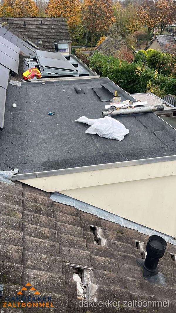 Verouderd plat dak met slijtage tussen schuine daken in Zaltbommel Verouderd plat dak met slijtage tussen schuine daken in Zaltbommel